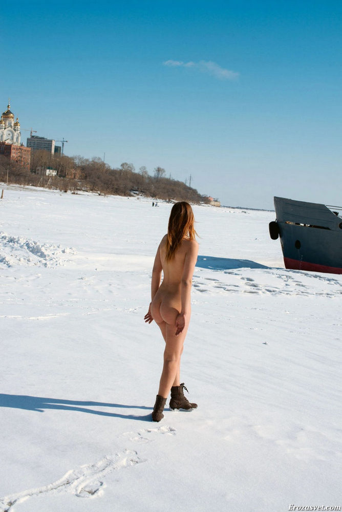 Голенькая девочка у старых лодок на замерзшей реке