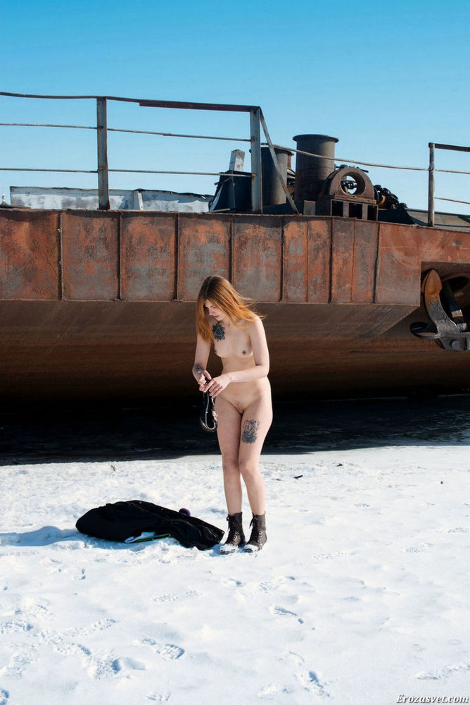 Голенькая девочка у старых лодок на замерзшей реке