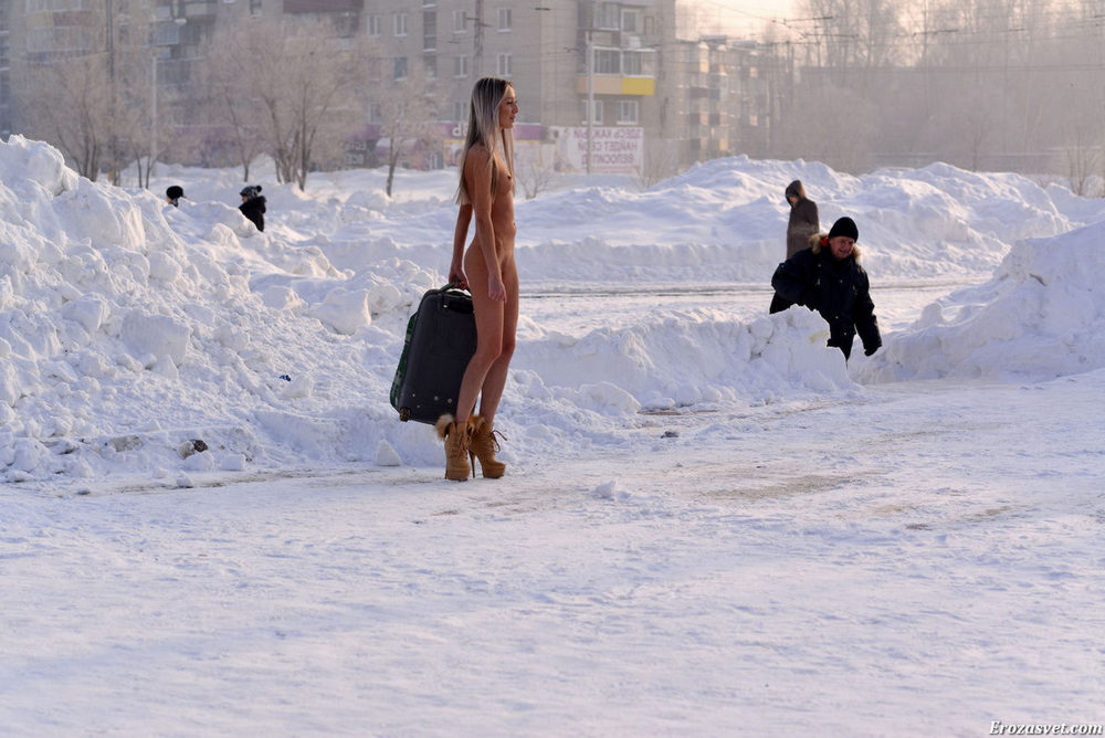 Стройная девушка раздевается на улице среди снега