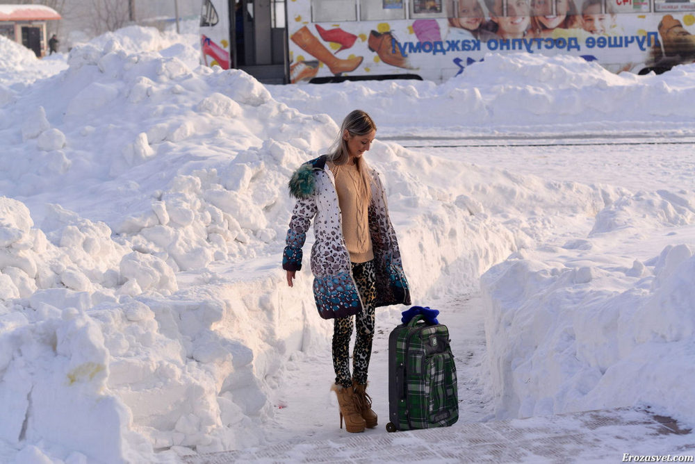 Стройная девушка раздевается на улице среди снега